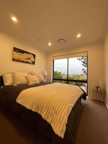 a bedroom with a large bed with a large window at 3 Bedroom House in Cooma in Cooma