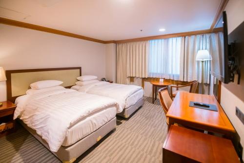 a hotel room with two beds and a desk at Hotel International Changwon in Changwon