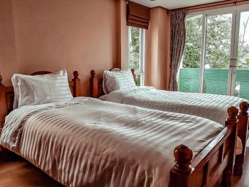 two twin beds in a bedroom with a window at One Deves in Bangkok