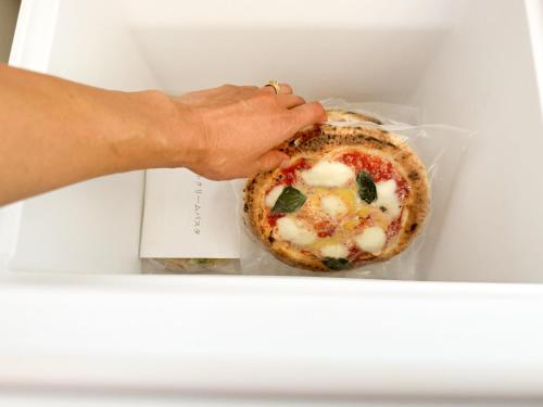 a person holding a small pizza in a box at HOLLY CAMP CASA in Akagina