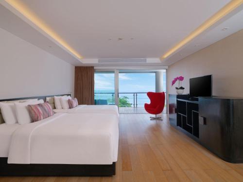 a bedroom with a large white bed and a red chair at Double - Six, Luxury Hotel - Seminyak in Seminyak