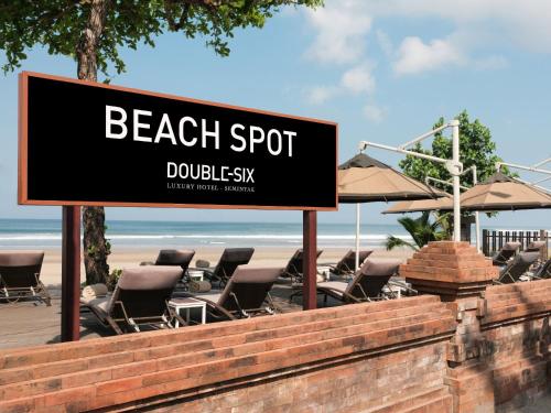 a sign in front of a beach spot with chairs and umbrellas at Double - Six, Luxury Hotel - Seminyak in Seminyak