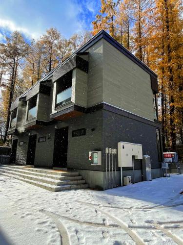 a black building with snow in front of it at Queens Park CK Village Niseko Hirafu in Kutchan