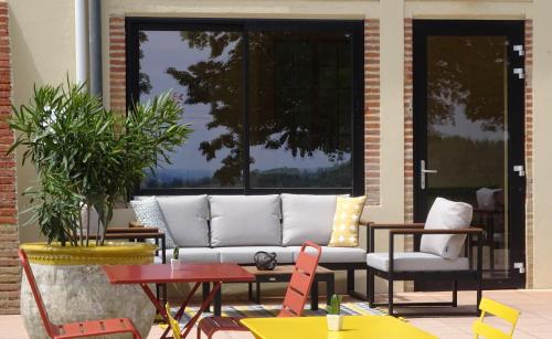 a couch on a patio with tables and chairs at Aux Coteaux d'Aussac in L Honor De Cos