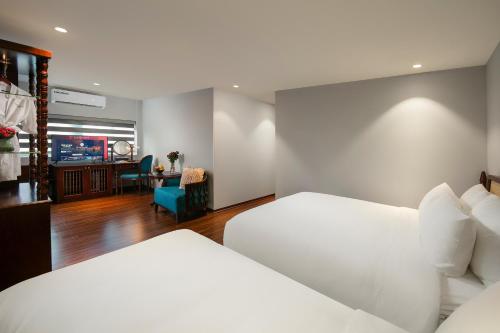 a hotel room with two beds and a desk at Serene Central Hotel in Hanoi