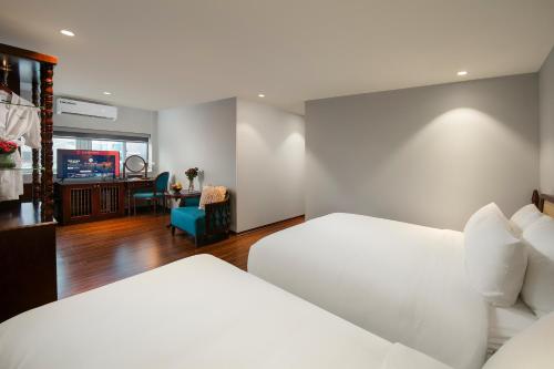 a hotel room with two beds and a desk at Serene Central Hotel in Hanoi