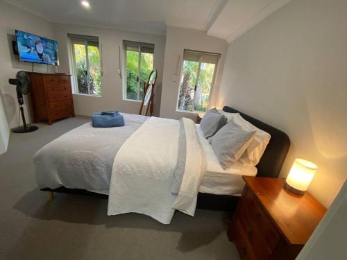 a bedroom with a large white bed and two windows at Halls Head Serene in Mandurah