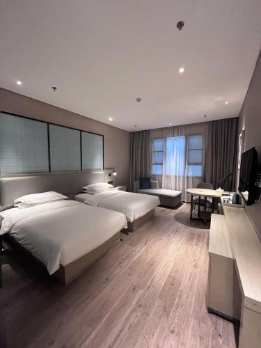 a hotel room with two beds and a desk at Echarm Hotel Kunming Baita Road Huidu International Store in Kunming