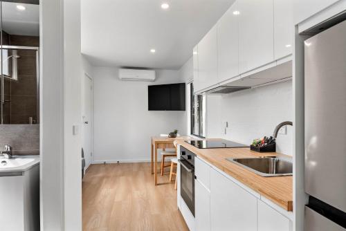 a kitchen with white cabinets and a wooden counter top at Beach Haven San Remo in San Remo