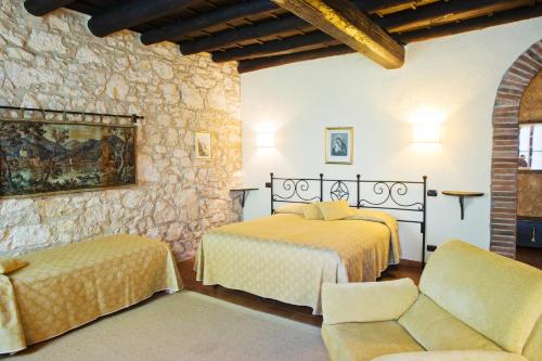 a bedroom with two beds and a stone wall at I Costanti in Caldiero