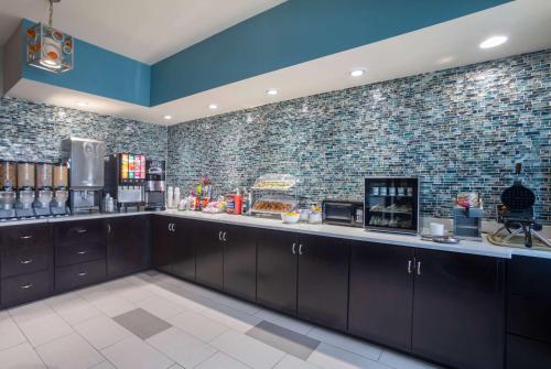 a kitchen with black cabinets and a brick wall at La Quinta by Wyndham Oxford - Anniston in Oxford