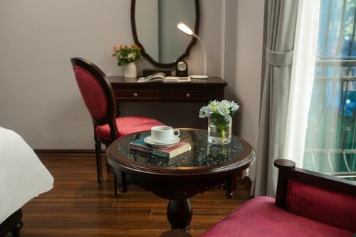 a room with a desk and a table with a cup and books at Serene Central Hotel in Hanoi