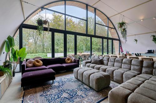a living room with couches and a large window at Bosresort Maanzicht in Noordwolde