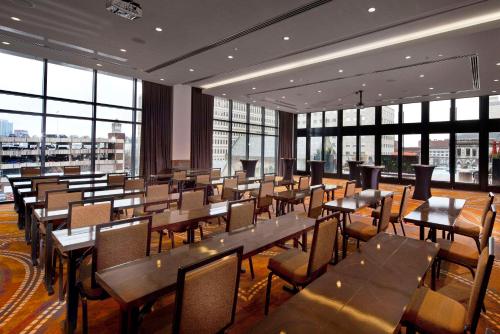 a restaurant with tables and chairs and large windows at Cambria Hotel Nashville Downtown in Nashville