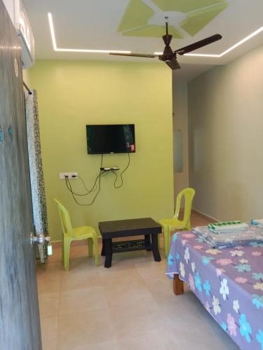 a room with a bed and a tv on the wall at Sai Ram Cottage in Alibaug