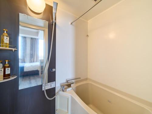 a bathroom with a bath tub and a shower at Meitetsu Inn Kariya in Kariya