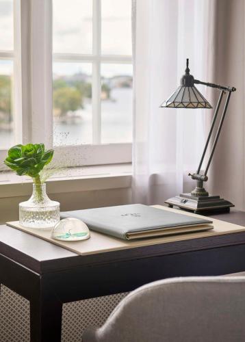 a desk with a lamp and a book on it at Hôtel Reisen in The Unbound Collection by Hyatt in Stockholm