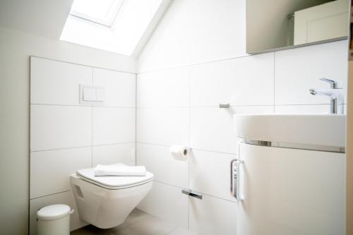 ein weißes Badezimmer mit Toilette und Waschbecken in der Unterkunft Kapitänshaus - Boje in Born