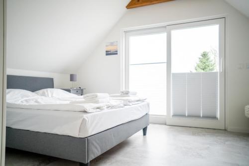 ein weißes Schlafzimmer mit einem Bett und einem großen Fenster in der Unterkunft Kapitänshaus - Boje in Born