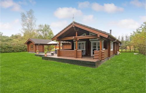 a log cabin with a deck in the grass at Holiday Home Ramshule Farsø Xii in Hvalpsund