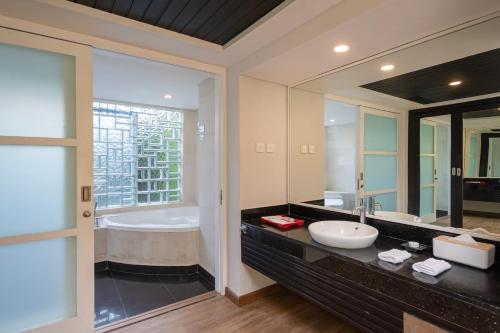 a bathroom with a sink and a tub and a mirror at Prime Plaza Hotel Sanur – Bali in Sanur