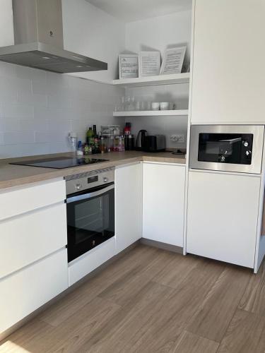 a kitchen with white cabinets and a stove top oven at The Nook at Monda in Monda