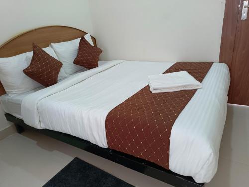a bedroom with a large bed with white and brown pillows at SM Residency in Bhubaneshwar