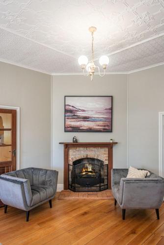 a living room with two chairs and a fireplace at The Ranch-pool Table, Table Tennis, Firepit, Piano in Stanthorpe