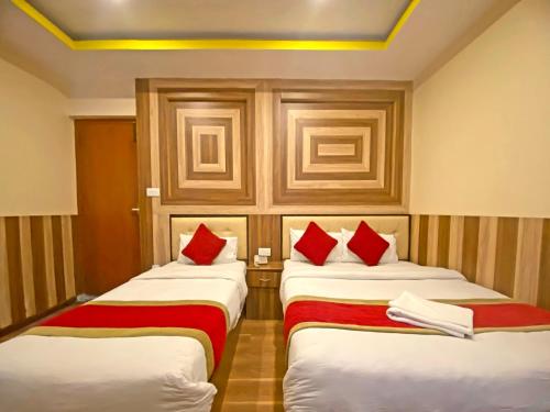 two beds in a hotel room with red pillows at Hotel Airport Holiday in Kathmandu