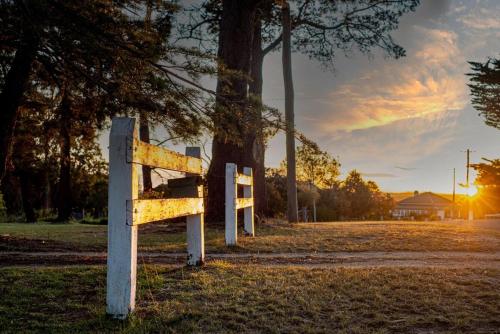 a bench in a field with the sunset in the background at The Ranch-pool Table, Table Tennis, Firepit, Piano in Stanthorpe