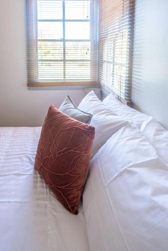 a bed with white sheets and a brown pillow on it at The Ranch-pool Table, Table Tennis, Firepit, Piano in Stanthorpe