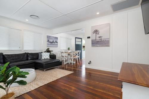 a living room with a black couch and a table at Acacia Ridge Cottage - Firepit, Kids Cubby, Games in Brisbane
