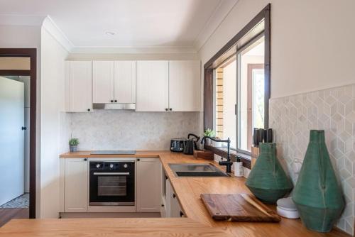 a kitchen with white cabinets and a wooden counter top at Creek View Cottage-pool table, table tennis, views in Stanthorpe
