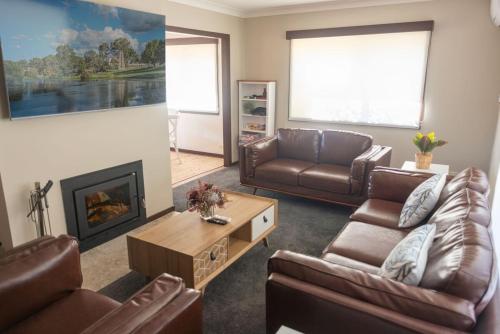 a living room with leather furniture and a fireplace at Creek View Cottage-pool table, table tennis, views in Stanthorpe