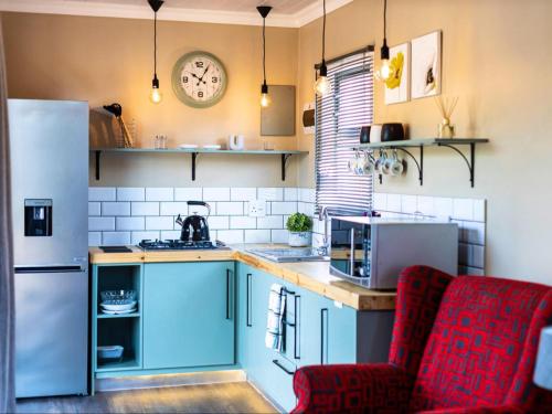 a kitchen with blue cabinets and a white refrigerator at The Den On Plover in Velddrif
