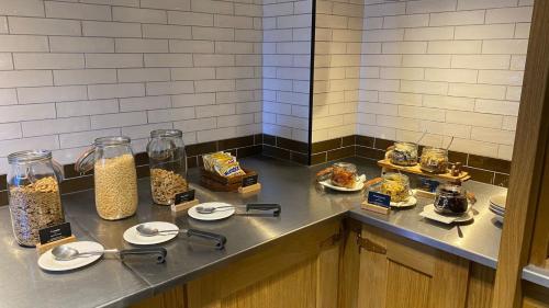 a counter with plates of food and jars of food at voco Leicester by IHG in Leicester