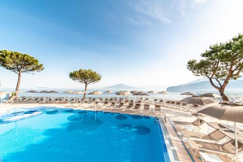 a swimming pool with chairs and umbrellas at Grand Hotel President in Sorrento