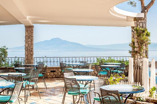 a patio with tables and chairs and a view of the ocean at Grand Hotel President in Sorrento