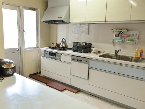 a kitchen with a sink and a stove top oven at ゲストハウス星風 in Suo Oshima