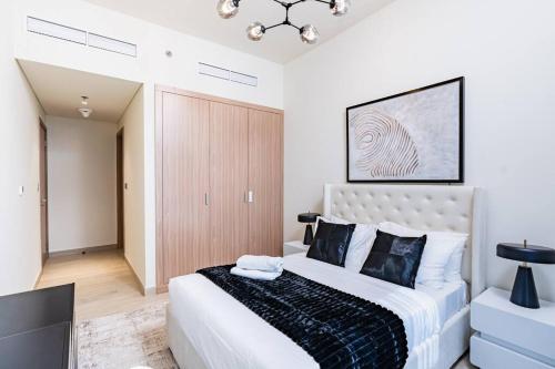 a bedroom with a large white bed and a chandelier at Nasma - Modern 3BR Oasis with Balcony in Azizi Riviera in Dubai