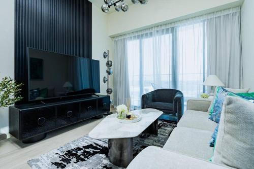 a living room with a large television and a couch at Nasma - Modern 3BR Oasis with Balcony in Azizi Riviera in Dubai