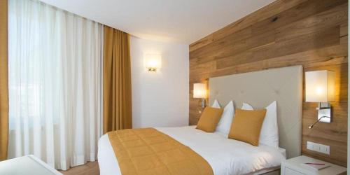 a bedroom with a large white bed with yellow pillows at Hotel Schweizerhof Pontresina in Pontresina