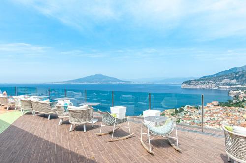 a row of chairs and tables on a balcony overlooking the water at Grand Hotel President in Sorrento