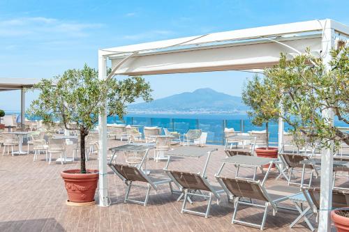a patio with tables and chairs and the ocean at Grand Hotel President in Sorrento