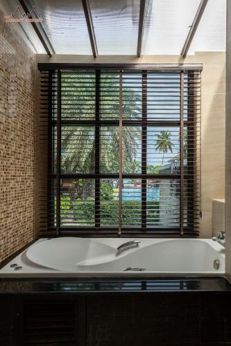 a bath tub in a bathroom with a large window at Tommy Resort in Haad Rin