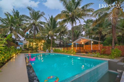 a swimming pool in a resort with palm trees at EKOSTAY - Serenity Villa in Alibaug