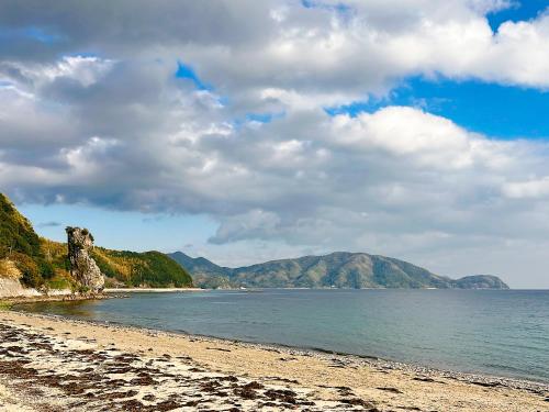 a view of a beach with mountains in the background at ゲストハウス星風 in Suo Oshima