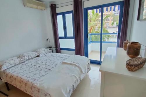 Un dormitorio con una cama y una ventana grande en Sunny, center Albir apartment, en Alfaz del Pi