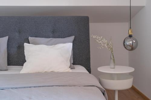 1 dormitorio con 1 cama con cabecero gris y mesa en MIA Appartements, en Innsbruck