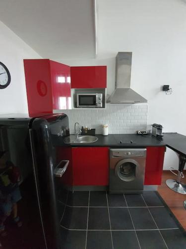 - une cuisine avec des placards rouges et un lave-linge dans l'établissement Très joli appartement Disneyland Paris 4 pers, à Bussy-Saint-Georges